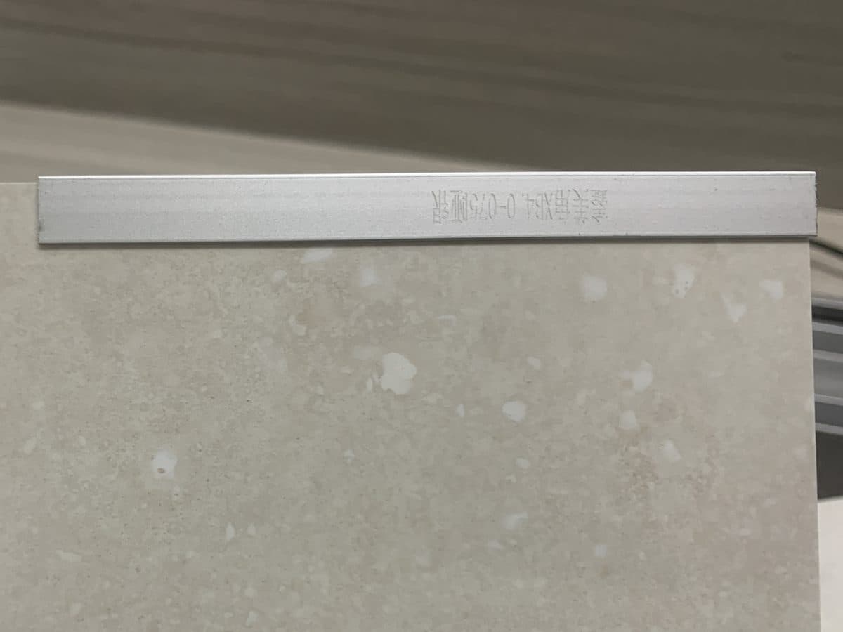 Wall panel edge trim fitted to the top edge of an SPC wall panel, silver